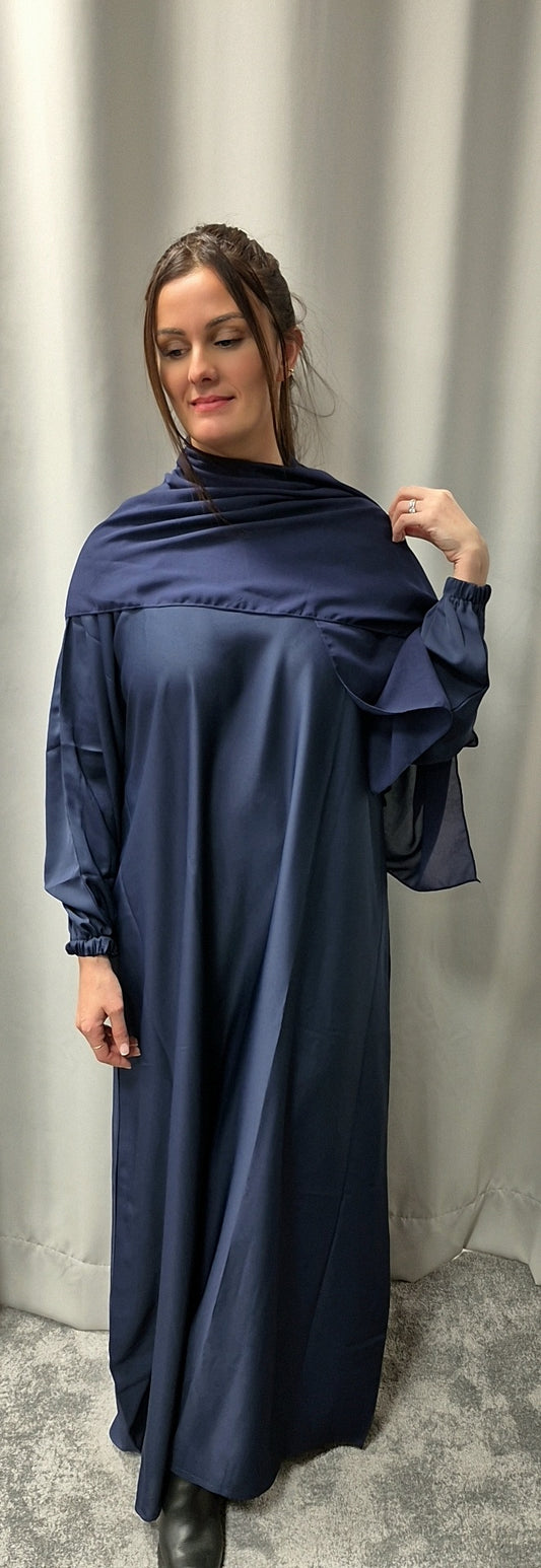 A woman wears the Bihi Boutique Stylish Navy Blue Abaya with Chiffon Hijab (Size 58) indoors, her hair partly up and a slight smile on her face.