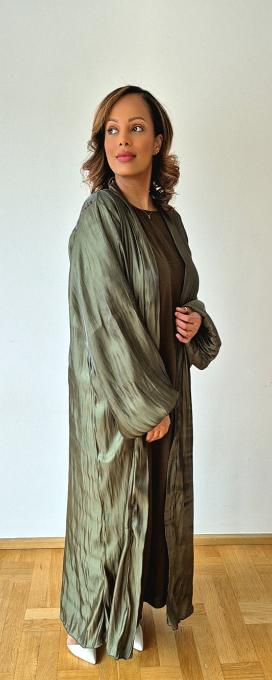 A woman stands on a wooden floor, wearing the Bihi Boutique Organza Zaytun Slipdress & Chiffon Hijab in size 58, styled with white shoes and posing against a plain light background.