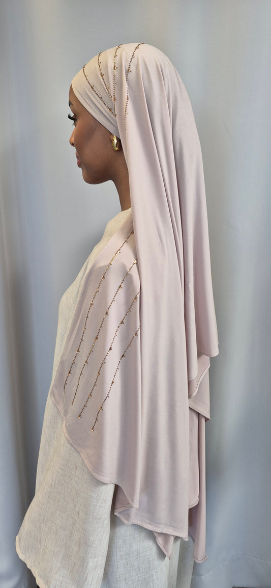 A woman in profile wears the Shop Premium Jersey Bianca hijab by Bihi Boutique, featuring delicate gold lines and paired with a cream, loose-fit top against a simple light background, reflecting ultimate comfort and style.