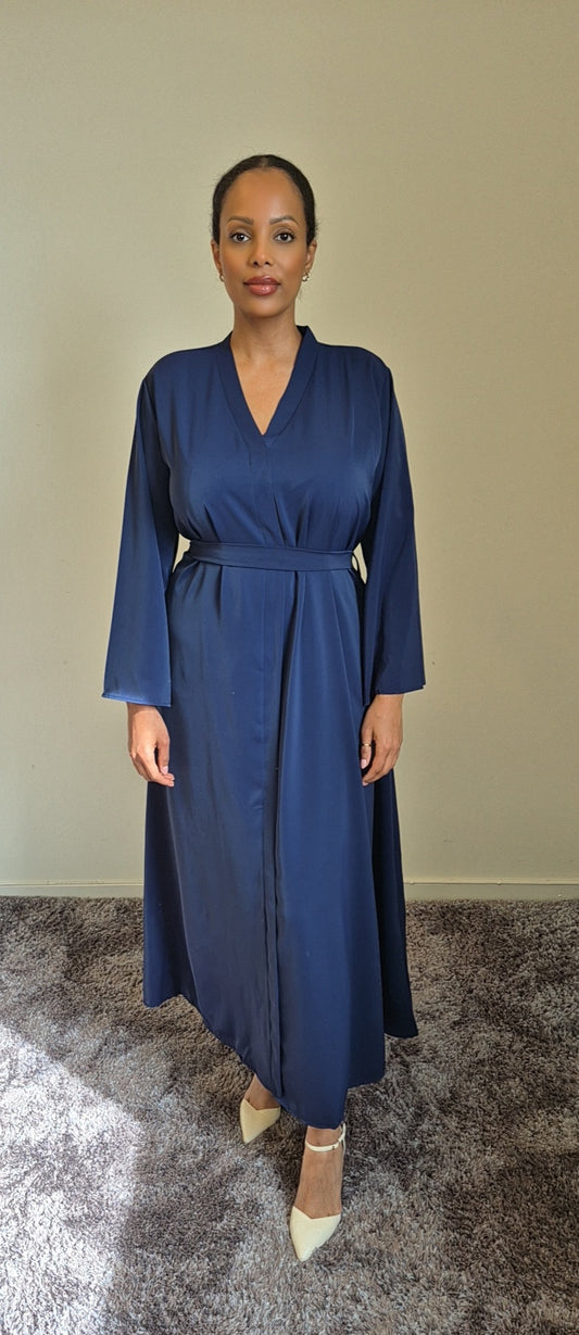 A woman stands indoors on a carpet, wearing the Shop Layina Black Dress from Bihi Boutique in L/XL, with her hair pulled back and a neutral expression.