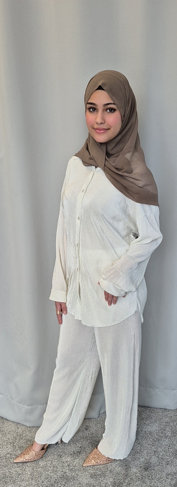 A woman wearing the Bihi Boutique Stylish Black Opal Co-ord Set (Fashionable One Size) stands on a gray carpet before a light gray curtain, smiling confidently with one hand on her hip.