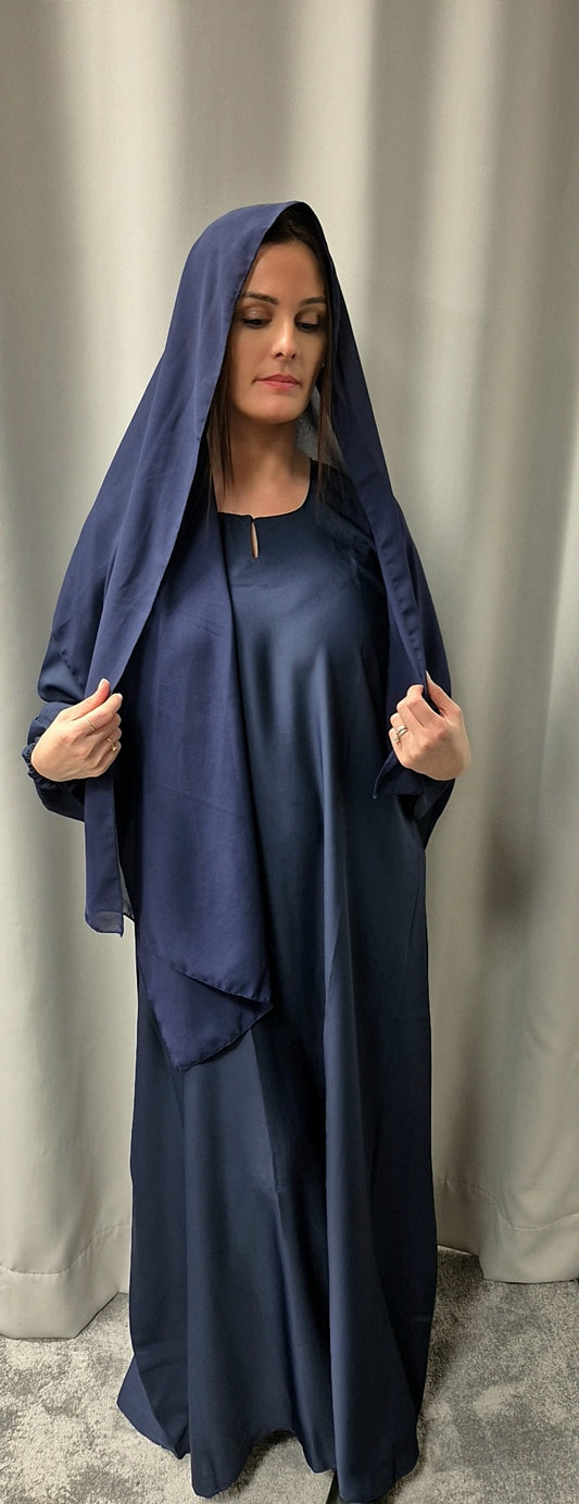 A woman stands in front of a curtain, eyes closed, wearing the Bihi Boutique Stylish Navy Blue Abaya with Chiffon Hijab (Size 58), holding the matching hijab draped over her head and shoulders.