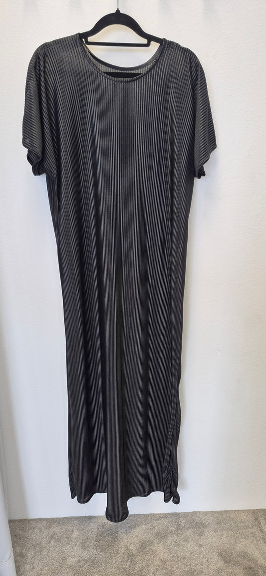 The Chic Black Slip Dress by Bihi Boutique, featuring short sleeves, a loose fit, thin white diagonal stripes, and a subtle bottom knot, hangs on a black hanger against a plain white wall. It falls below the knee—effortless style for any occasion.
