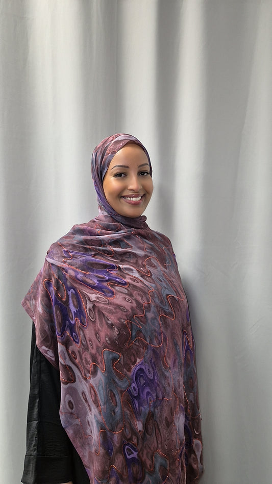 A woman in the Elegant Chiffon Hijab from Bihi Boutique smiles at the camera while standing before a plain light gray curtain.