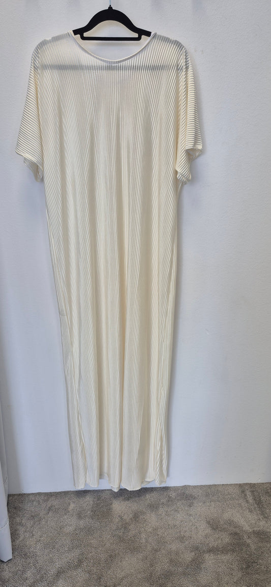 The Elegant White Slip Dress (Size 58) by Bihi Boutique hangs on a black hanger against a white wall, with beige carpet below—its short sleeves and pleated design make it perfect for any occasion.