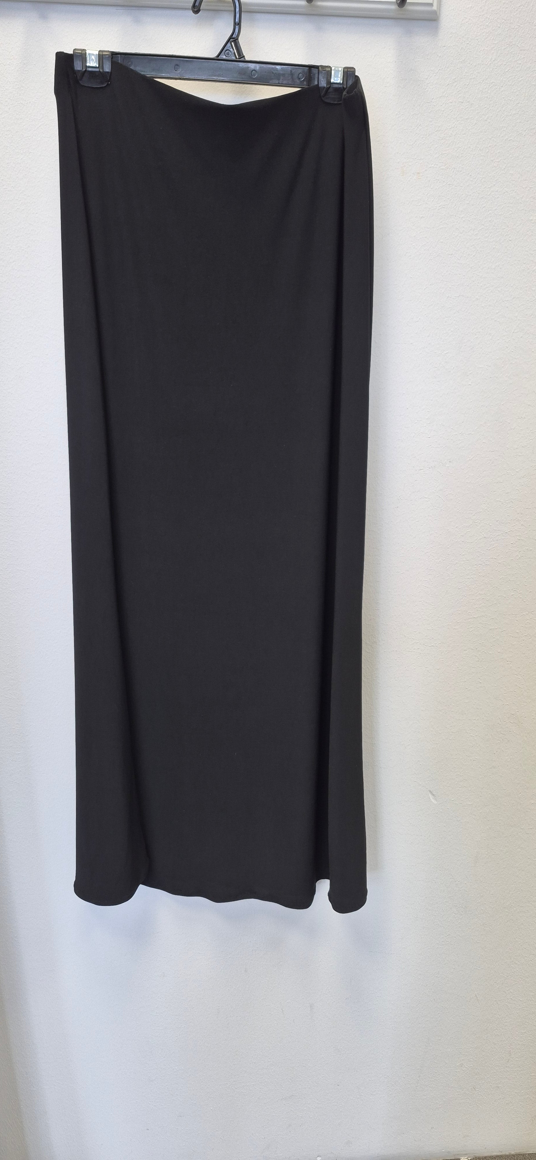 The Bihi Boutique Maxi Stretchy Skirt in size L, non-tight, hangs on a hanger against a white wall.