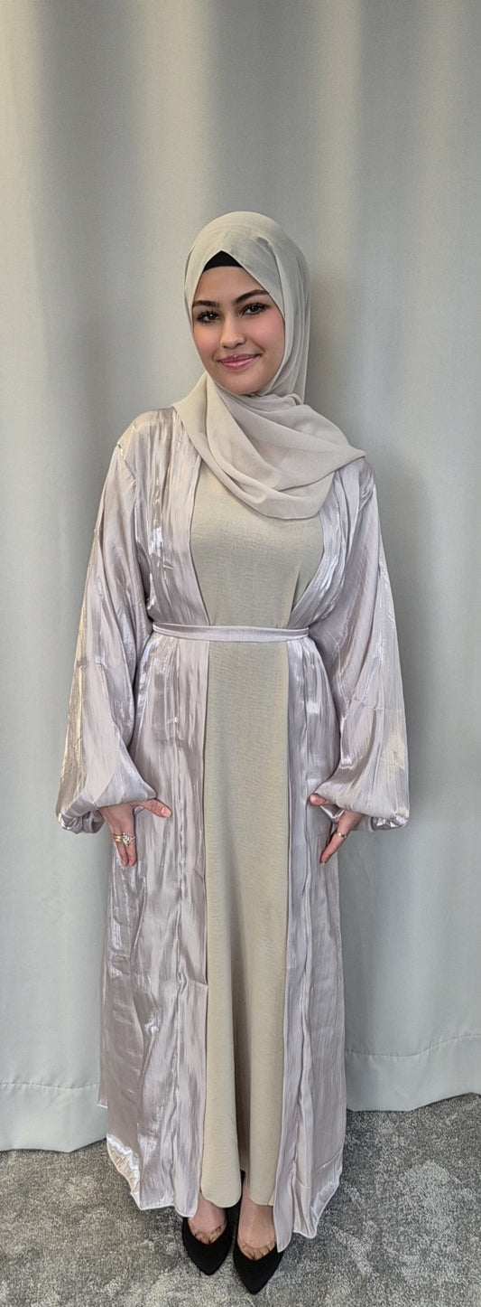 A woman smiles gently at the camera, wearing the Bihi Boutique Stylish Organza Chrome Hijab Set—a chic, lightweight fashion ensemble—in front of a plain light curtain.