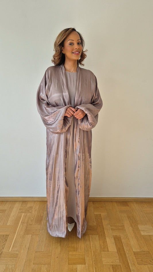 A woman stands indoors on a wooden floor, smiling and wearing the Elegant Organza Nude Slipdress with a Chiffon Hijab by Bihi Boutique (Size 58), set against a plain white wall.