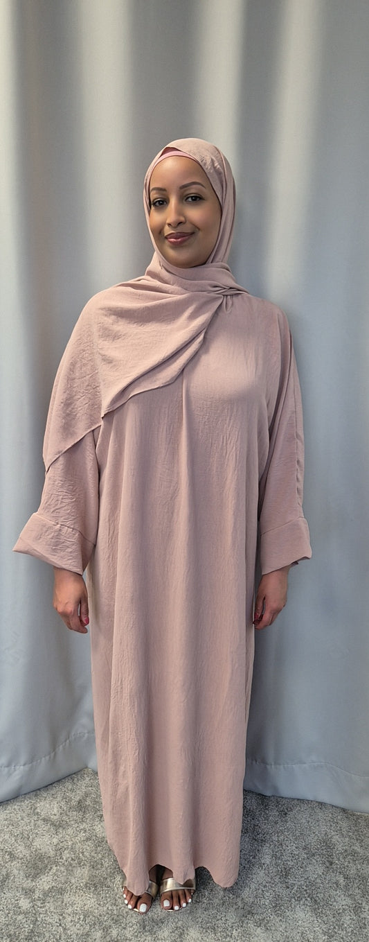 A woman wearing Bihi Boutiques Elegant Black One Size Prayer Clothing stands on a gray carpet before a light gray curtain, smiling softly at the camera.